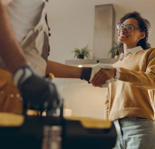 AdobeStock_694858134-scale Close up of male handyman shaking hands with happy female client while standing at home kitchen